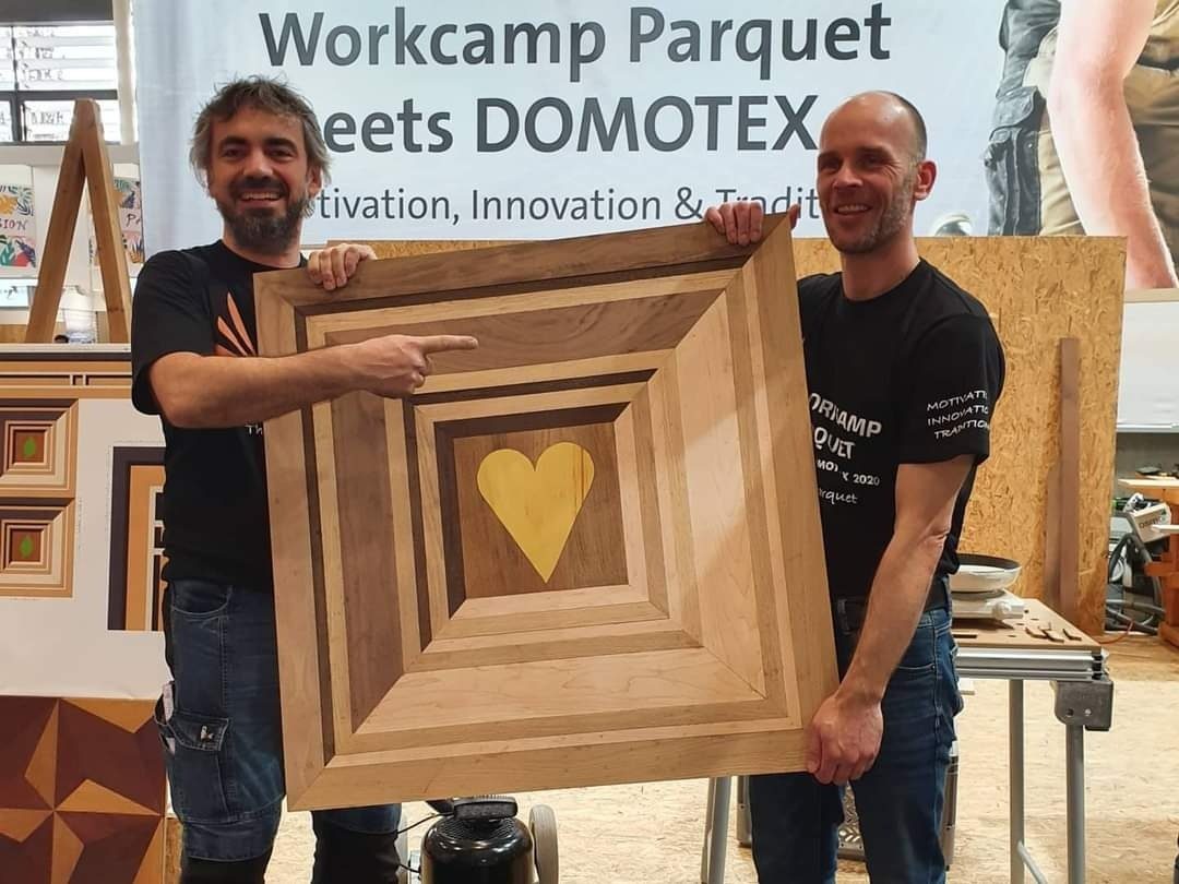 Jakko Woudenberg met een houten kunstwerk met hart-inleg op Workcamp Parquet, Domotex Hannover 2020