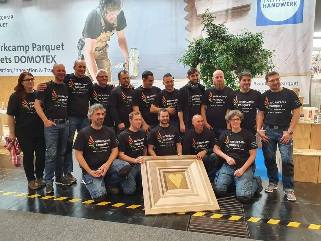 Team van Workcamp Parquet met het houten hart-kunstwerk, Domotex Hannover 2020